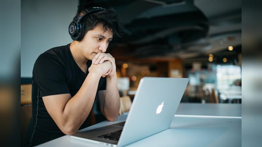 A man listening to something while looking at his laptop