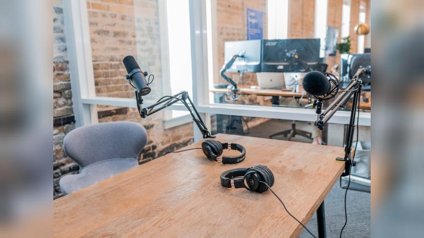 two microphones and two black headphones on a wooden table