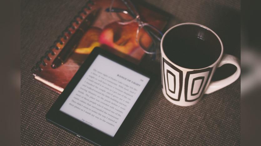 Black Kindle on a book and near a mug