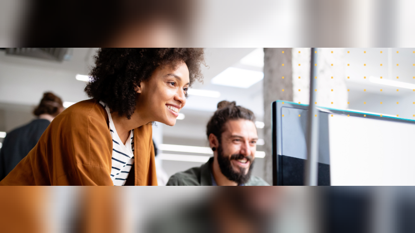 a man and a woman smiling at the computer