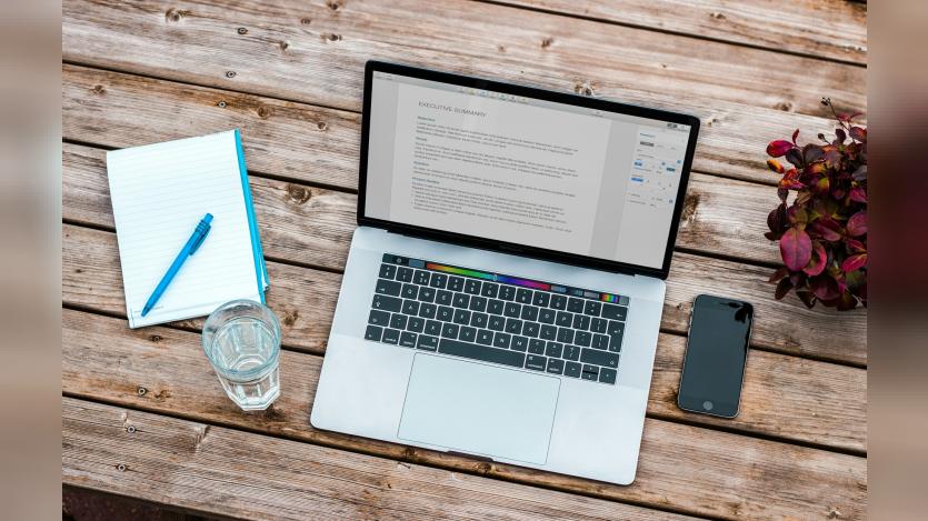 Macbook, mobile phone and notepad and a pen
