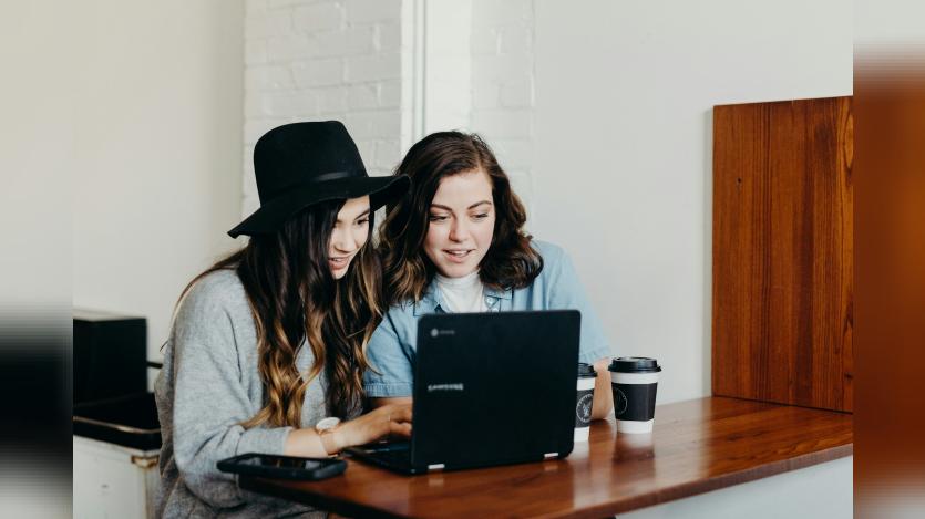 Two-woman-sitting-near-table-using-laptop