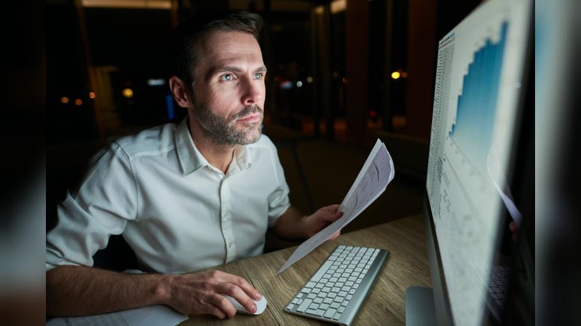 Focused man with document using computer