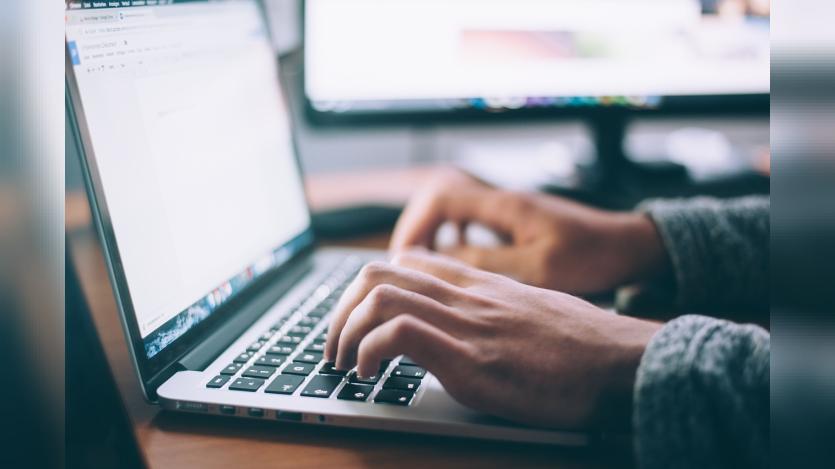 A pair of hands typing on a laptop