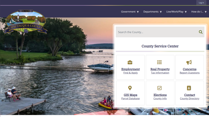 Chautauqua County New York website with navigation menu, search bar, and county service center options over a lakeside sunset background
