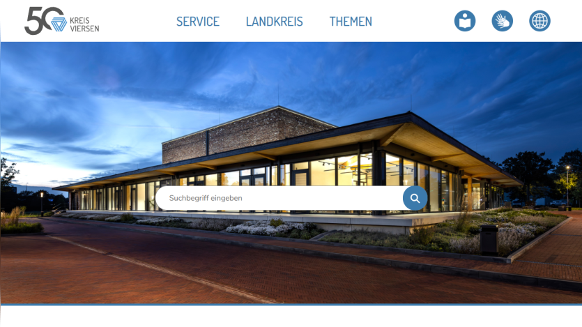 Kreis Viersen website with navigation links and a search bar over a modern building at dusk.