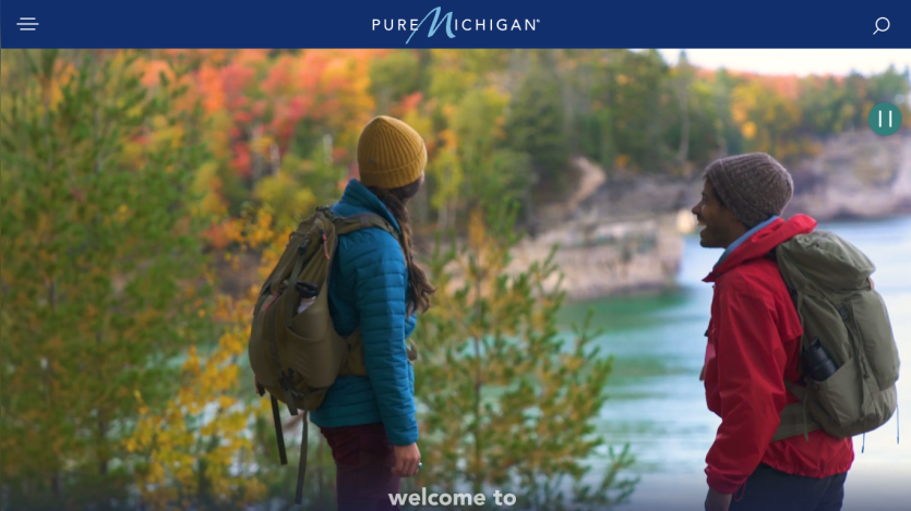 Two hikers overlooking a colorful autumn landscape by a lake.