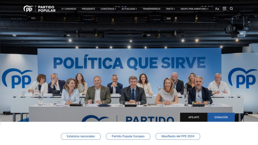 Political party event with a group of people seated at a table under the slogan 'POLÍTICA QUE SIRVE' and party logos