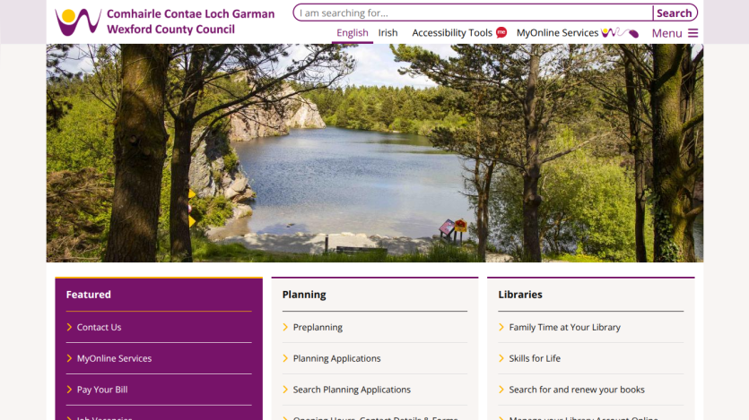 Wexford County Council homepage with search bar, navigation links, and a scenic lake view hero image