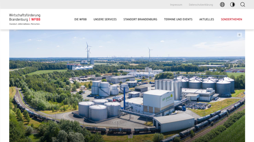Economic development site in Brandenburg with industrial buildings, wind turbines, and train tracks