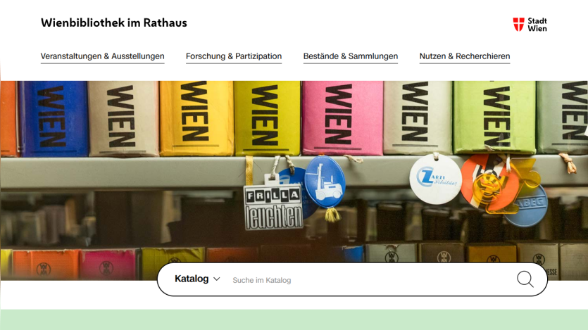 Wienbibliothek im Rathaus website with navigation links and a colorful book spine hero image above a catalog search bar