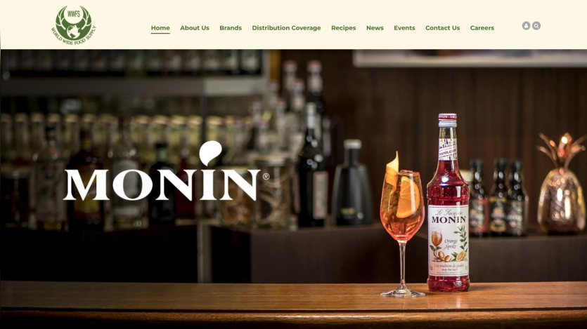 World Wide Food Supply website header with navigation and Monin syrup bottle and cocktail on bar counter