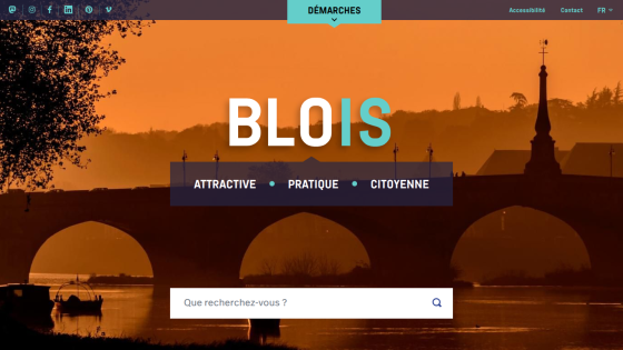 City of Blois website with navigation, social media links, and search bar over a sunset bridge background