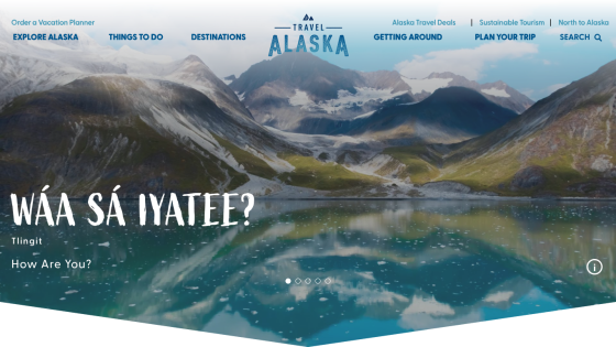 Homepage of Travel Alaska featuring a scenic landscape and greeting in native language.