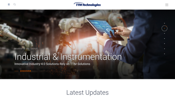 TTM Technologies homepage featuring Industrial & Instrumentation market solutions with a person using a tablet and robotic arms in the background