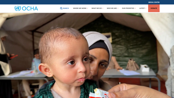 Child receiving food assistance in a humanitarian setting, with adults in the background.