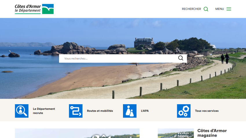 Côtes d'Armor tourism website with search bar, coastal landscape hero image, and navigation links