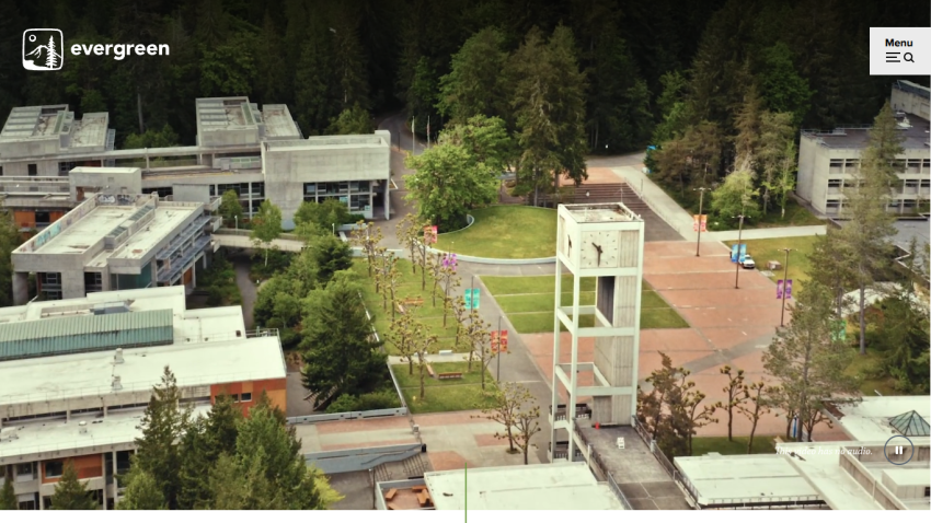 Aerial view of a college campus with buildings and a clock tower in a green setting.