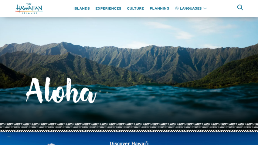 Aloha greeting with scenic mountain and ocean view on a travel website.