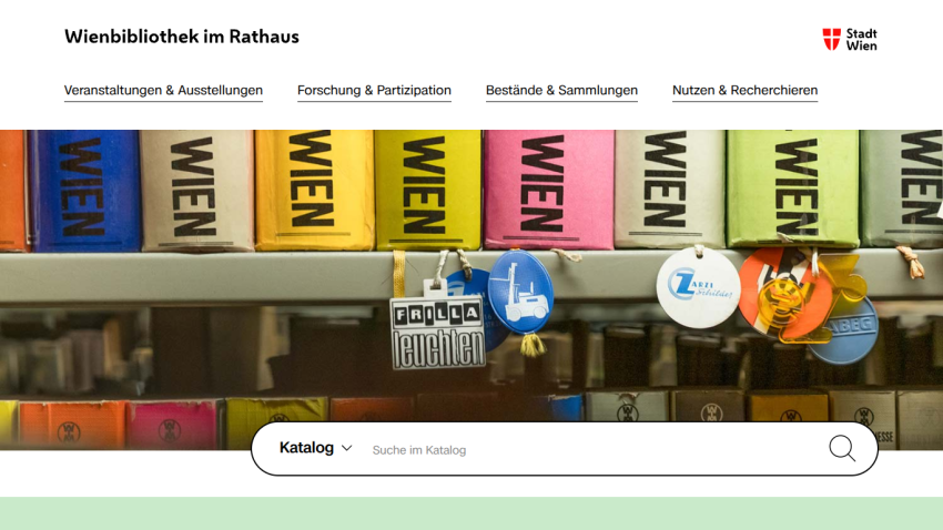 Wienbibliothek im Rathaus website with navigation links and a colorful book spine hero image above a catalog search bar
