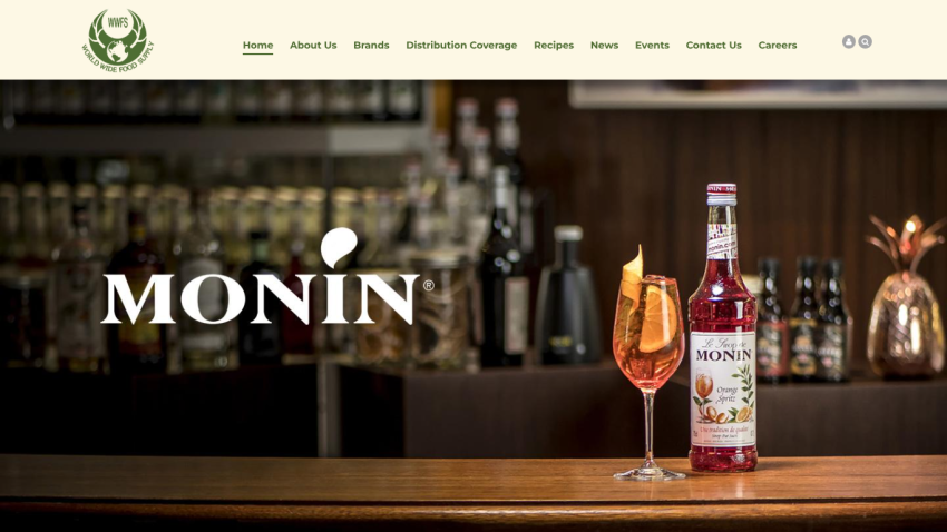 World Wide Food Supply website header with navigation and Monin syrup bottle and cocktail on bar counter