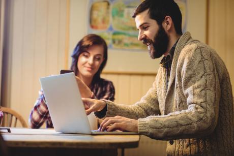 Couple interacting while using laptop and mobile phone