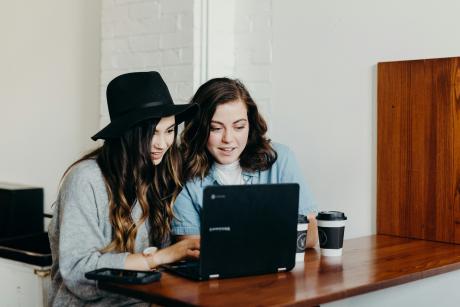 Two-woman-sitting-near-table-using-laptop