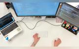  A person working on 2 systems and a laptop simultaneously