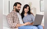 husband and wife on couch going through laptop